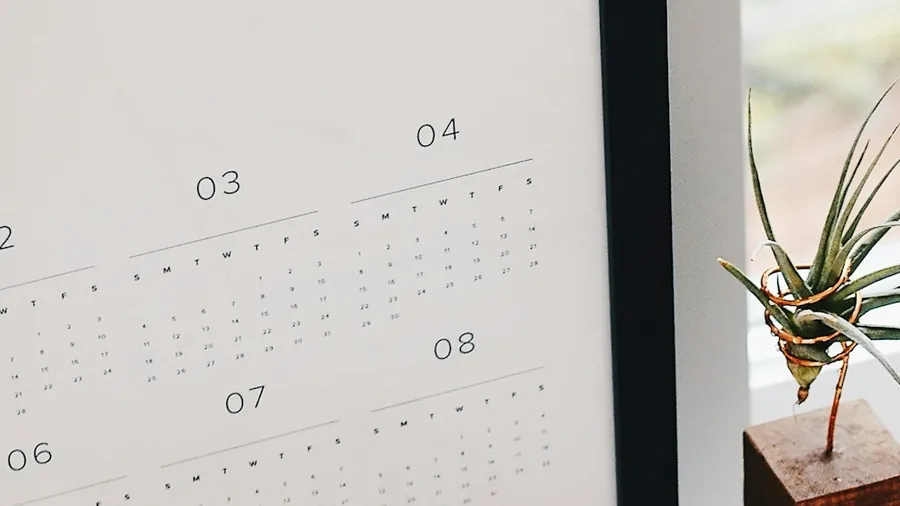 A wall calendar and a planner on a desk