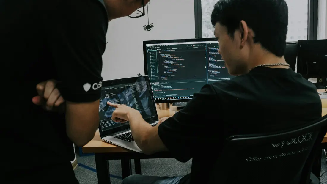 Two engineers working on computers in a tech office