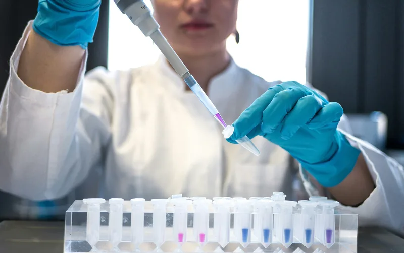 Scientist using a pipette with a rack of test tubes in a laboratory