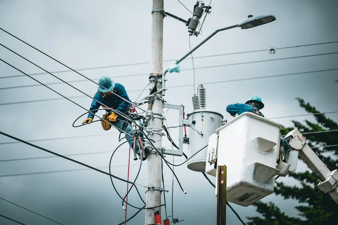 Utility linemen working on a power pole from a bucket truck